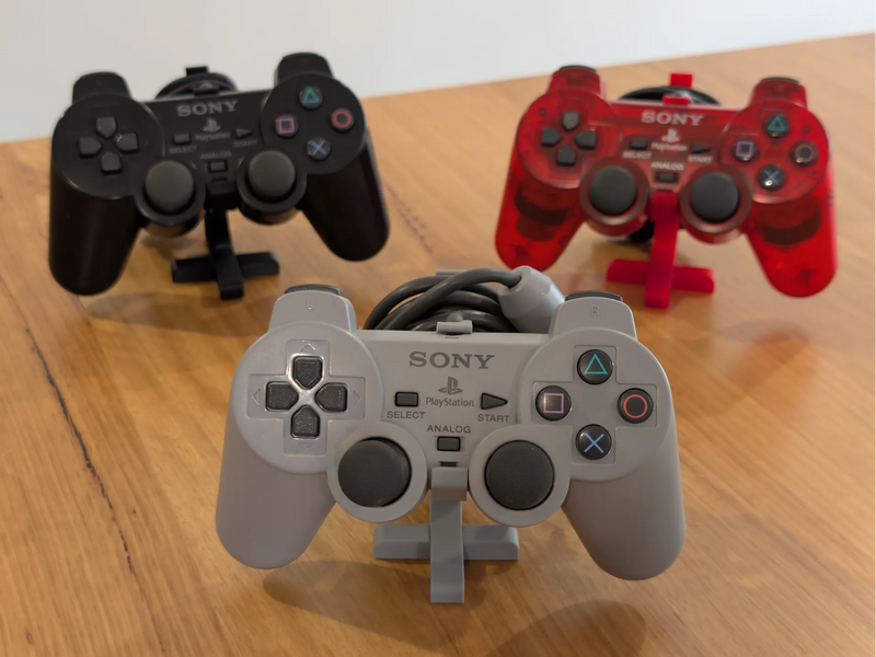 PlayStation DualShock and DualShock 2 controllers, each on a Retro Craft controller display stand
