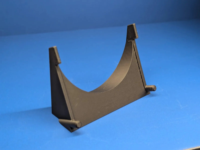 Black 3D printed Sega Game Gear display stand shown on its own, with a curved cradle and front lip that holds the handheld upright