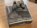 Xbox 360 S console on its display stand, with a controller held in the built-in holder